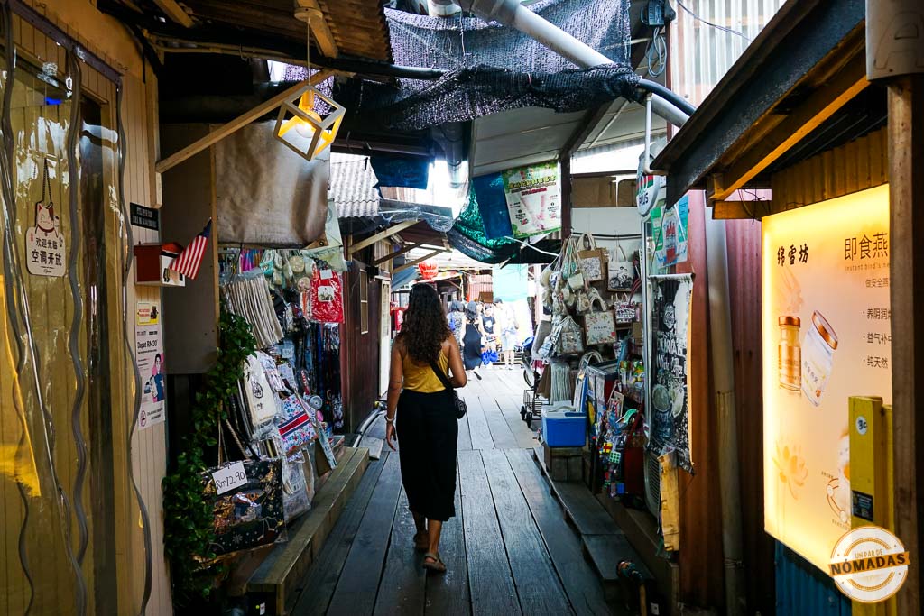 Viajera caminando por la pasarela de madera del Chew Jetty, flanqueada por casas tradicionales y tiendas de souvenirs en Georgetown, Penang.