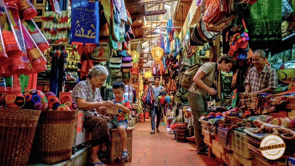 Turista interactuando con un vendedor de artesanías en los abarrotados y coloridos pasillos del Mercado Ruso (Tuol Tompoung) en Phnom Penh.