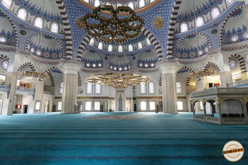 Interior de la inmensa Mezquita Central mostrando su suelo cubierto con una gran alfombra turquesa y techos con decoración otomana en tonos azules, un templo espectacular que ver en Bishkek