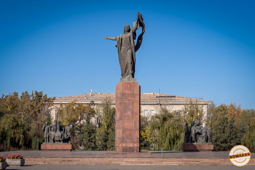 Gran estatua central de bronce de la heroína Urkuya Salieva liderando la revolución en una plaza rodeada de árboles, un monumento histórico que ver en Bishkek