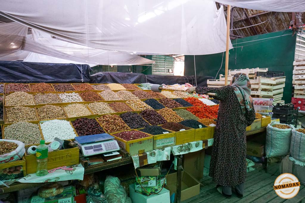 Mujer observando un inmenso y colorido puesto de frutos secos y especias en el animado Osh Bazar, el mercado tradicional más famoso que ver en Bishkek