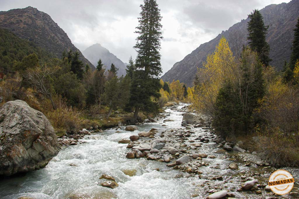 Caudaloso río de montaña fluyendo entre rocas y árboles otoñales en el Parque Nacional Ala Archa, una excursión imprescindible de naturaleza que ver cerca de Bishkek