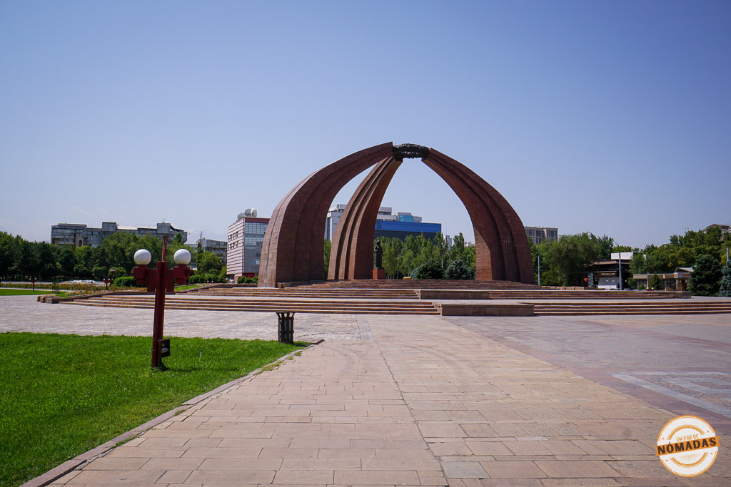 Gran monumento de piedra roja con forma de yurta tradicional sobre una plataforma escalonada en la Plaza de la Victoria, un importante lugar histórico que ver en Bishkek