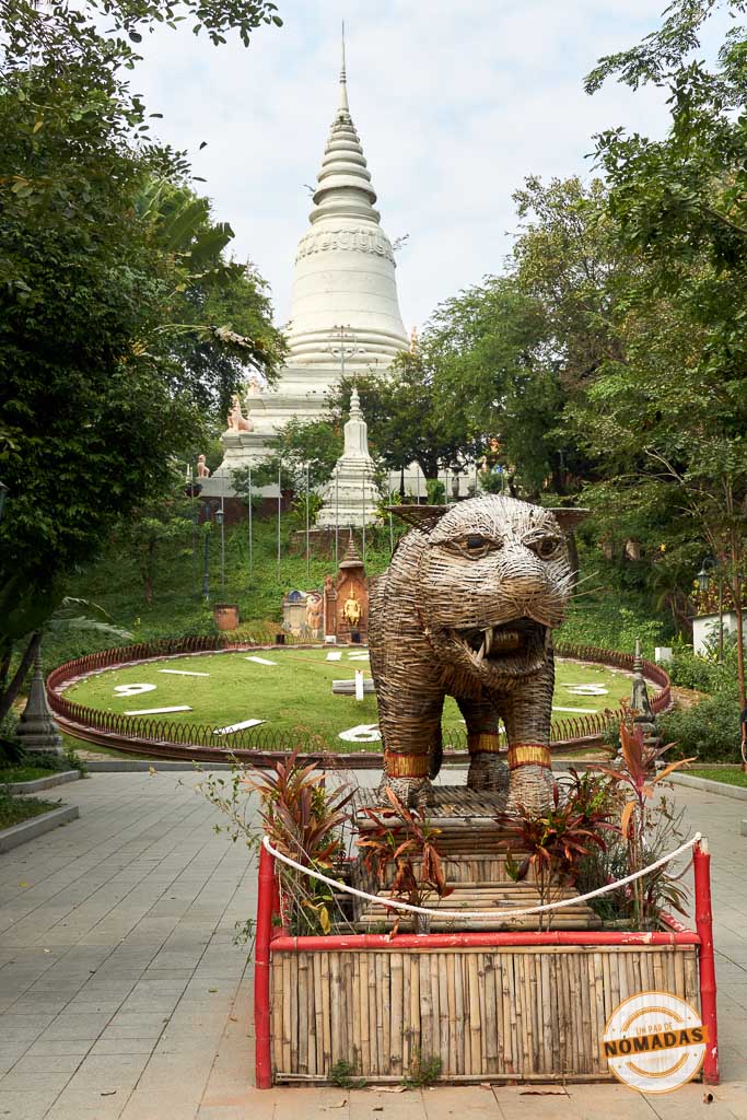 Estatua de tigre de mimbre y gran reloj floral en la base de la colina donde se alza la estupa blanca del templo Wat Phnom en Phnom Penh.
